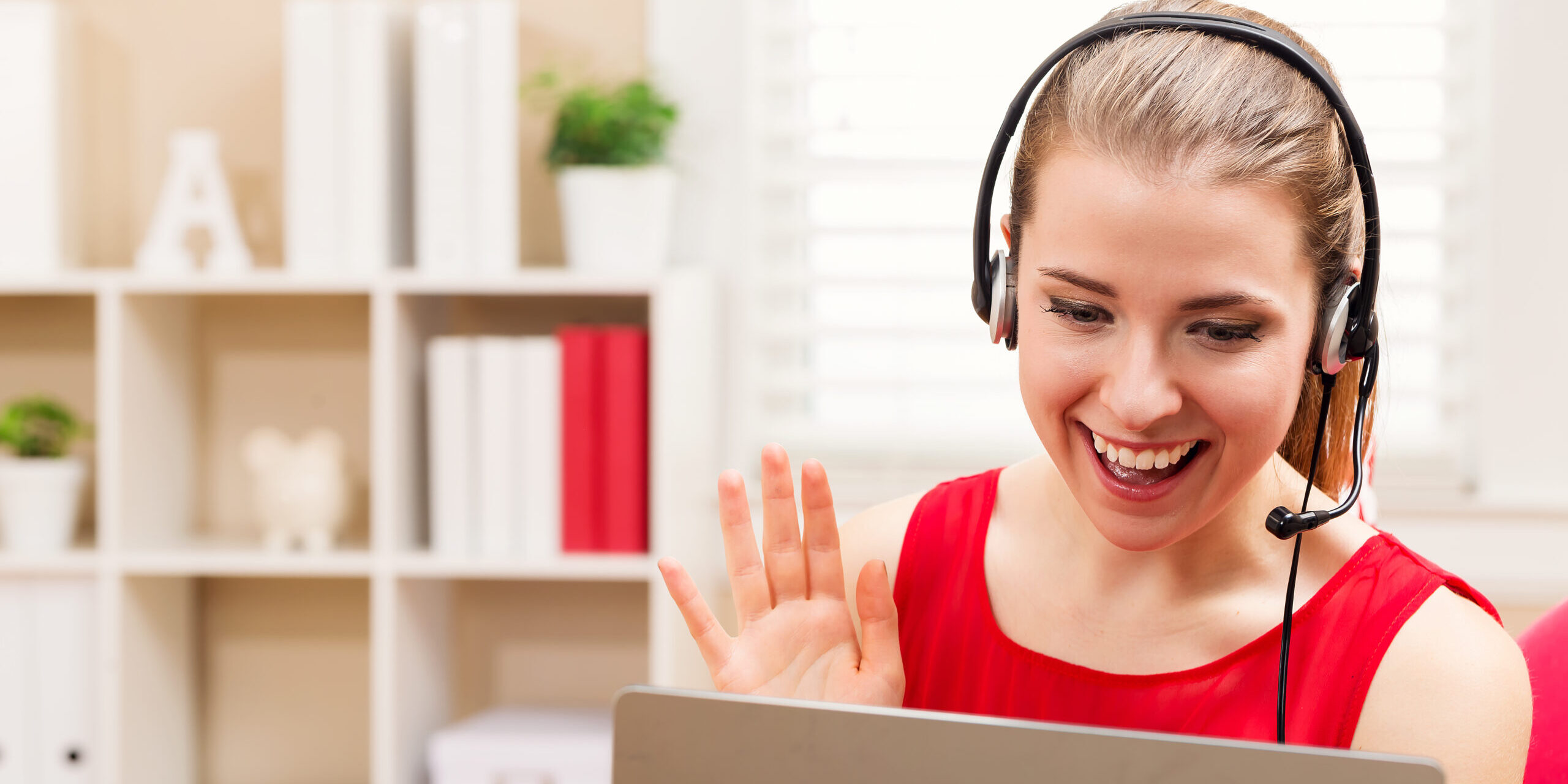 Happy young woman with headset talking on her laptop